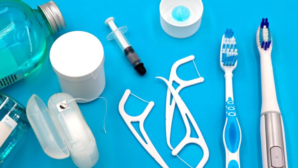 Whitening Strips and Floss Worth Adding to a Daily Routine Floss picks, dental floss, mouthwash and toothbrushes arranged on a blue surface