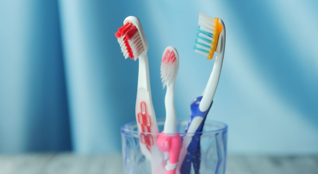 Toothbrushes standing in a small holder beside a folded towel on a bathroom counter