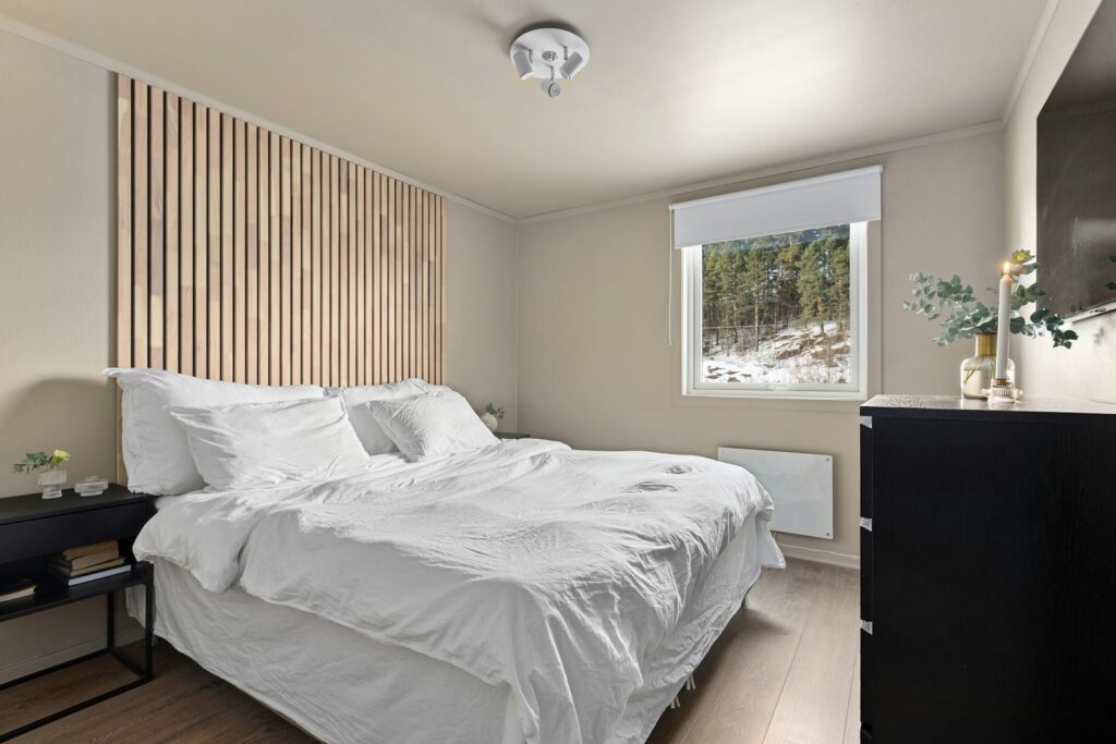 Avskalat hotellrum med träribbvägg och fönster mot snöiga tallar
