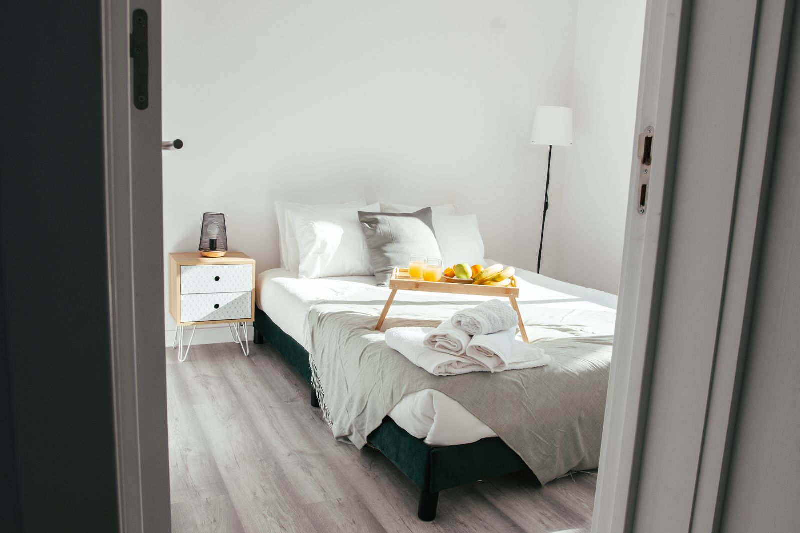 Avskalat vitt hotellrum med frukostbricka på sängen