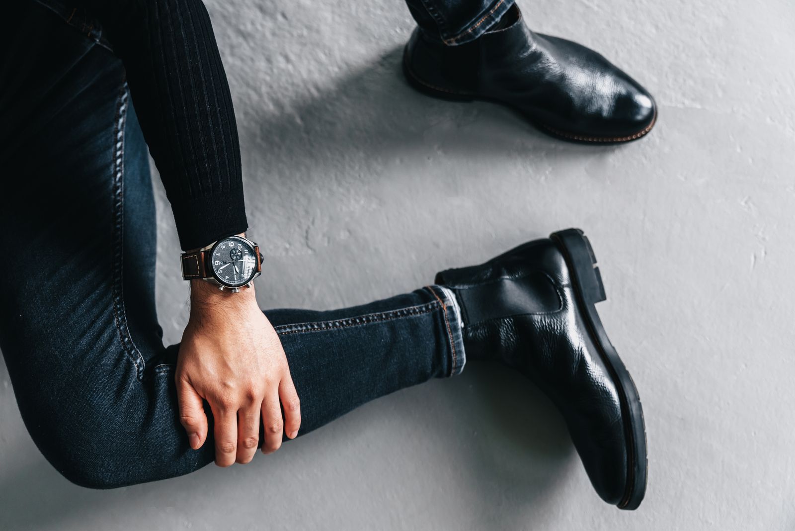 Men's Chelsea boots worn seated with jeans