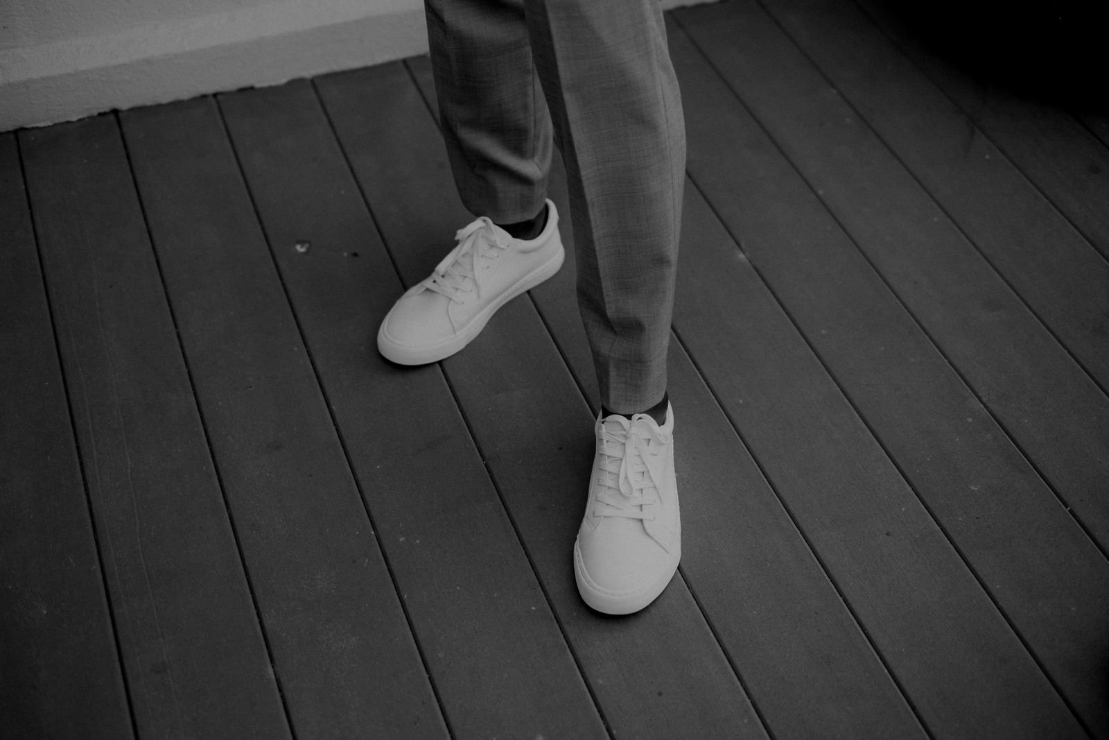 White minimal sneakers worn with tailored trousers
