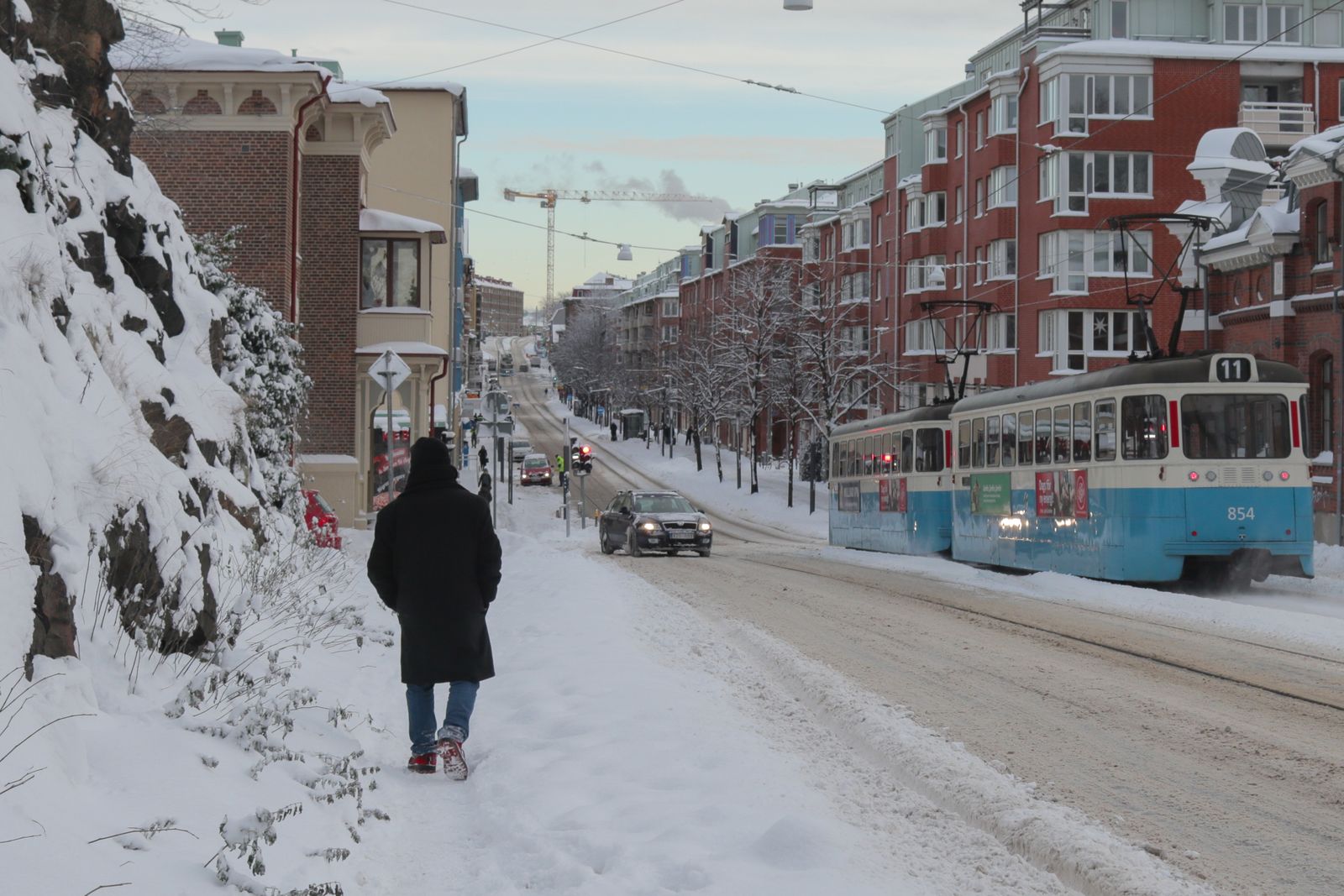 Tram running down a snowy city street past apartment blocks in Gothenburg